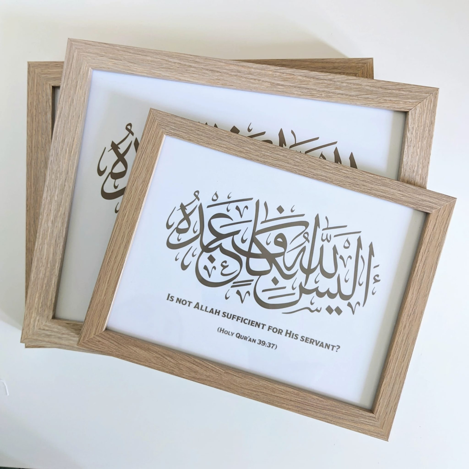 Three oak frames stacked, the top one reading Is not Allah sufficient for His servant, Quran 39:37