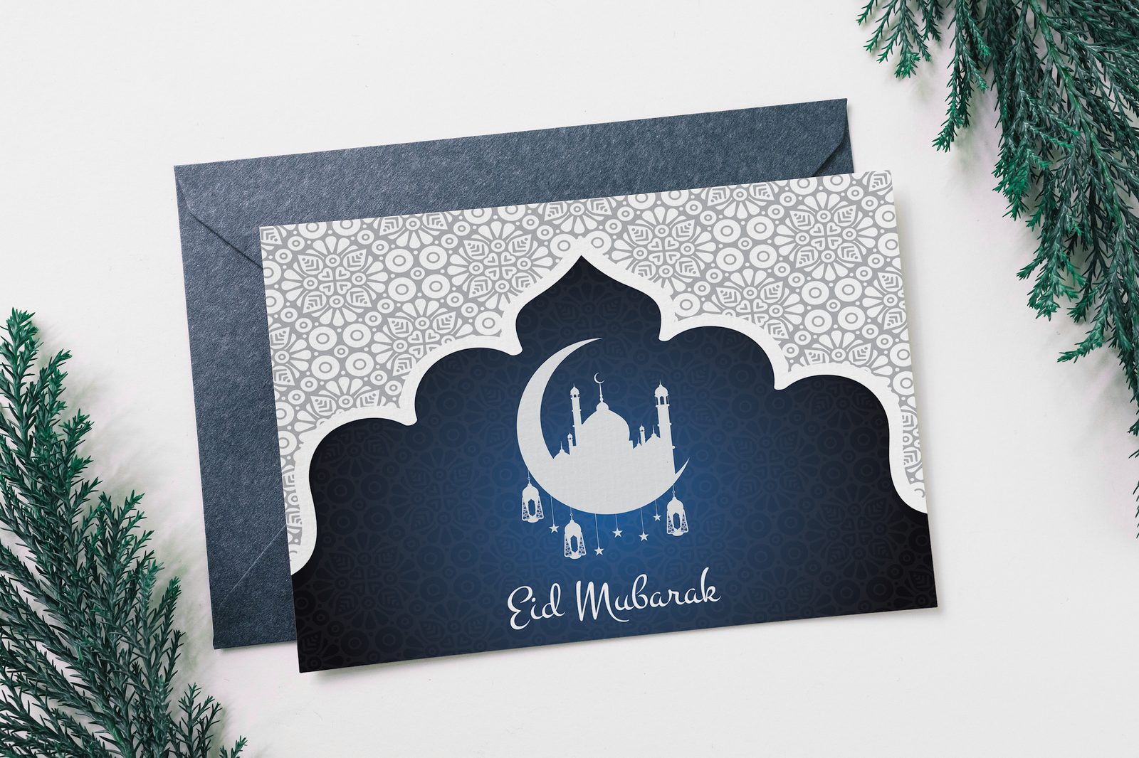 Navy Eid Mubarak greeting card with a mosque silhouette and lanterns, with its envelope