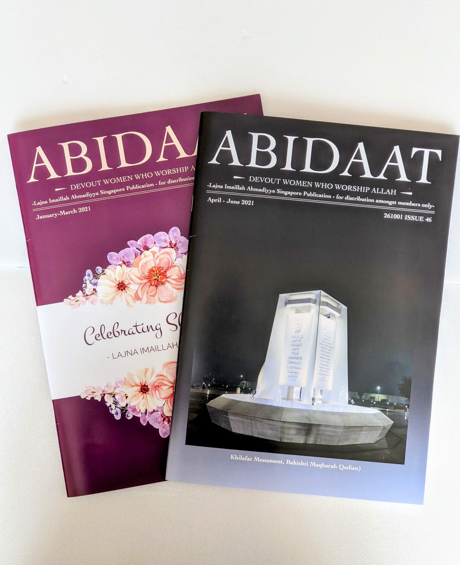 Two Abidaat covers, one purple with a floral band, one dark blue with a night photograph of a monument